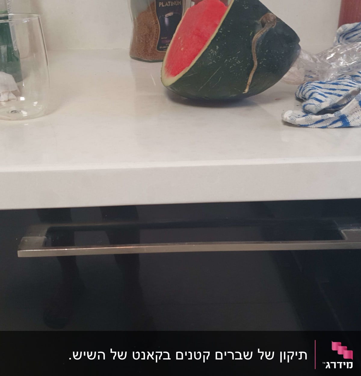 משטח שיש לבן עם כוס זכוכית וחצי אבטיח